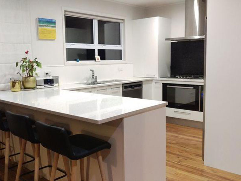 New modern kitchen with stone benchtop and rimu flooring.
